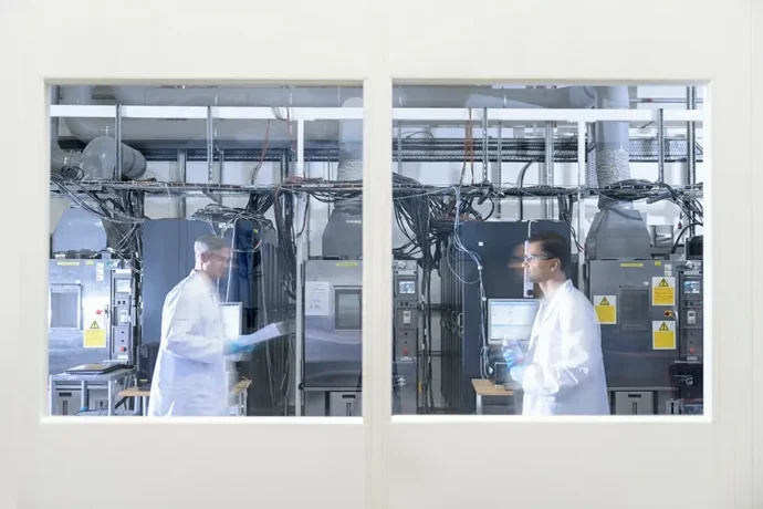 A window overlooking two scientists in a lithium ion battery research lab