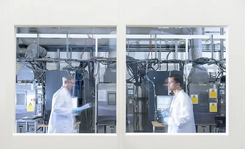 A window overlooking two scientists in a lithium ion battery research lab